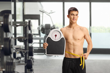 Naklejka premium Male teenager holding a weight scale and measure tape