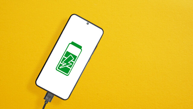 Phone quick charge is shown by Smartphone connected to a USB charging cable and fast charging on orange background. Empty space for text