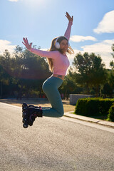 Happy sporty woman jumping with inline skates and headphones in park