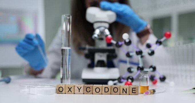 A dedicated researcher is meticulously studying oxycodone under a microscope in a specialized lab environment