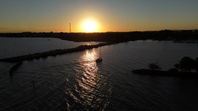 Veleiro retornando &agrave; marina durante o p&ocirc;r do sol na Lagoa dos Patos
