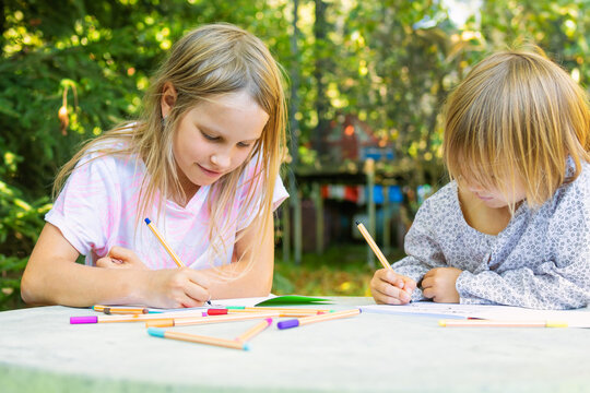 Sisters drawing and coloring together outdoors
