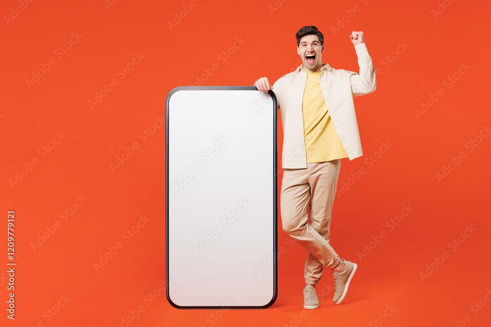 Poster Full body young man wear white shirt yellow t-shirt casual clothes big huge blank screen area mobile cell phone smartphone do winner gesture isolated on plain red orange background. Lifestyle concept.