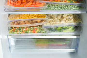 Plastic bags with different frozen vegetables in refrigerator, closeup