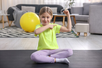Cute little girl showing her bicep indoors