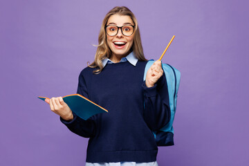 Young excited girl student wear blue casual clothes glasses backpack bag write down in exercise...