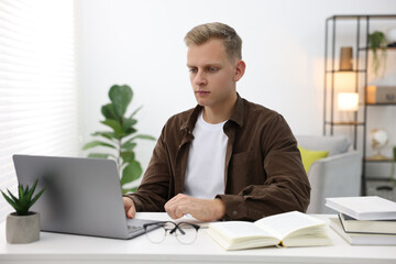 Student preparing for exam with laptop at table indoors