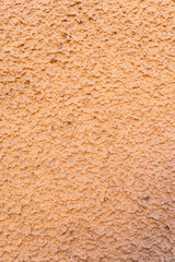 Close-up view of a textured orange wall surface, showcasing its rough and uneven patterns. The neutral background provides a minimalist aesthetic, ideal for use in design or creative projects.