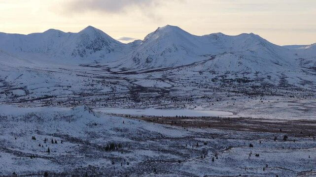 Dramatic aerial view of Fish Lake, surrounded by snow-covered mountains. The frosty Canadian wilderness radiates beauty under sub-zero skies.