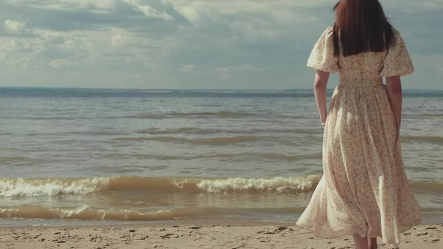 woman walking towards the sea on a cloudy day