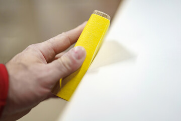 Sanding down burrs on a piece of furniture in a carpentry shop. Furniture manufacturing plant.