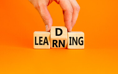 Learning or leading symbol. Concept words Learning Leading on wooden block. Beautiful orange table orange background. Businessman hand. Business learning or leading concept. Copy space.