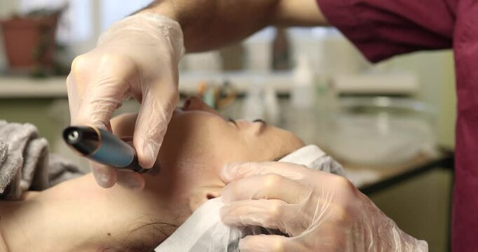 beautiful young woman on a facial dermapen micro-needling treatment at the beauty salon. Woman is getting a facial treatment with a device.
