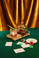 Poker night with whiskey and luxury vibes. Whiskey glass with chili garnish, playing cards, dice, and poker chips on green table. Concept of party, celebration, high-society, entertainment