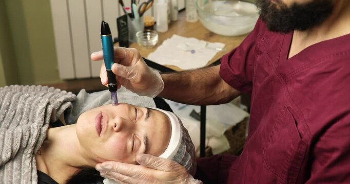 beautiful young woman on a facial dermapen micro-needling treatment at the beauty salon. Woman is getting a facial treatment with a device.