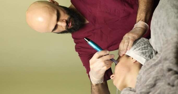 beautiful young woman on a facial dermapen micro-needling treatment at the beauty salon. Woman is getting a facial treatment with a device.