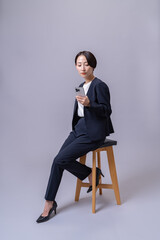 椅子に座り携帯を持つスーツを着た女性