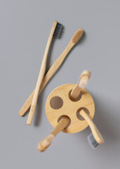 Beige bamboo toothbrushes in a holder on a light gray top view. Zero waste and no plastic