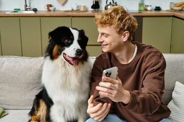 A young redhead man enjoys quality time with his Australian Shepherd in a cozy apartment.