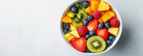 A colorful bowl filled with a variety of fresh fruits, including strawberries, blueberries, kiwi, and pineapple, arranged beautifully against a light background.