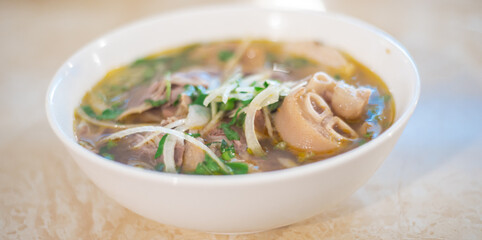 Panorama view traditional Bun Bo Hue noodles paired with tender slices of beef, pork broth, vermicelli round rice noodles, onions and fresh herbs, spicy soup with deep layer of flavor in Vietnam