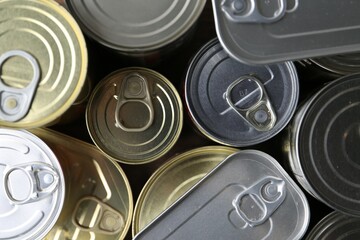 Many closed tin cans on wooden table, flat lay