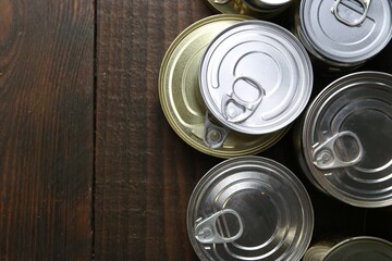 Many closed tin cans on wooden table, flat lay. Space for text
