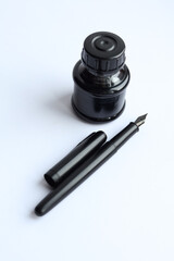 Black ink pen and ink bottle isolated on a white background with copy space
