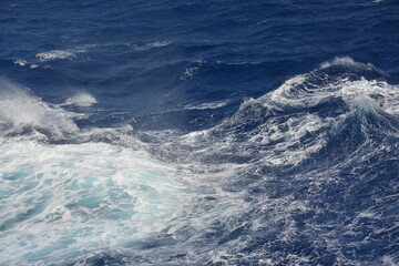 Choppy ocean waves with shades of deep blue and white foam. The dynamic movement of the water captures the power and turbulence of the sea