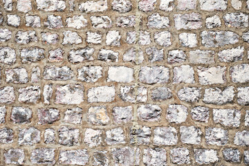 Rough stone bricks wall showing a close-up view of the stones and the mortar between them. Abstract patterns and textures