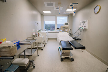 A modern hospital operating room with medical equipment, surgical table, sterile environment, storage carts, and a window with a view..