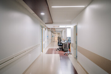 A clean and bright hospital corridor with white walls, medical equipment, and desks, creating a sterile and professional healthcare environment.