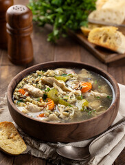 Bowl of chicken and rice soup on wooden table