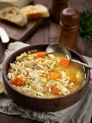 Bowl of chicken noodle soup with carrots on a napkin
