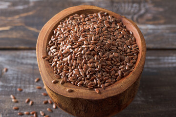 Flax seeds in a rustic wooden bowl on a wooden table with copy space