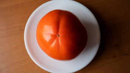 Bright orange fruit rests on a white plate in natural light