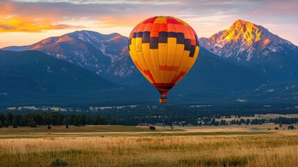 Obraz premium Vibrant Hot Air Balloon Floating Above Majestic Mountain Landscape at Breathtaking Sunset