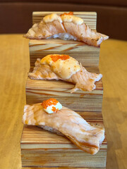 Close up of salmon sashimi sushi served on a wooden steps tray on a wood table. Japanese food theme.