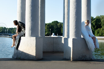 Two girls with black and white wings on a background of white columns.