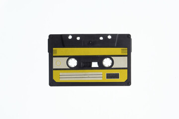 A vintage audio cassette tape with an yellow and black label, isolated on a white background,...