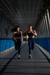 Two athletes running together under a bridge, showcasing synchronized motion and determination
