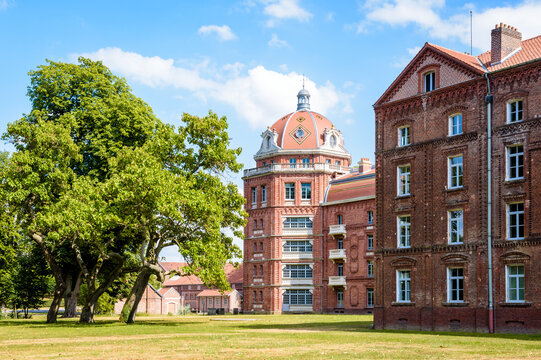 Guise, France - August 5, 2022: The rear of the Social Palace of the Familist&egrave;re, a phalanstery-type housing complex built by Godin in the 1860s, and its large domed tower overlook a tree-filled park.