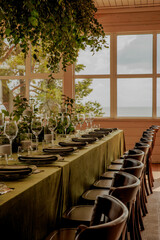 A table with plates, glasses, and chairs in a room with a window