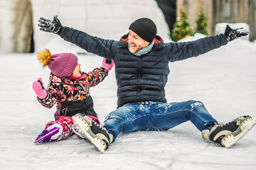Happy father and daughter on winter day learning skating