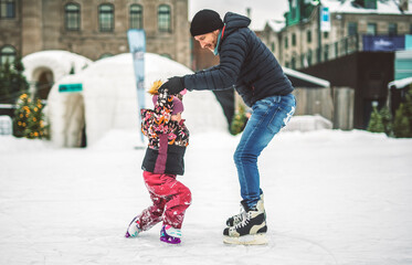 Happy father and daughter on winter day learning skating