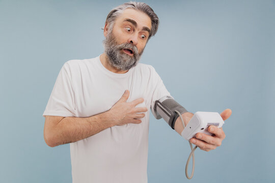 Shocked senior man checking blood pressure with portable medical device