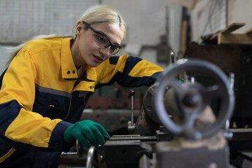 Factory woman worker at work in the industry factory, work with CNC machine. Factory female worker maintaining machine in the industrial factory. Female engineer checking parts of lathe machine