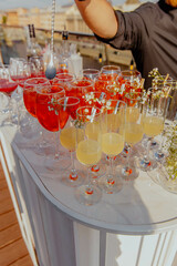 A bartender pours a drink into a line of wine glasses