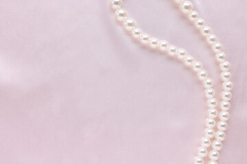 Elegant pearl necklace on pink fabric, top view. Space for text