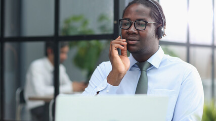 a man at a computer in a call center talking using headphones with a microphone